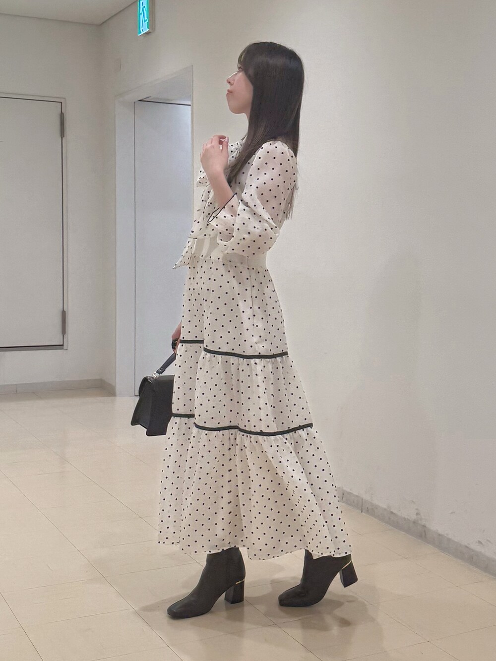 ホワイト系のワンピース、ブラウン系のハンドバッグ、ブラウン系のブーツを着用したレディースの冬コーディネートの4枚目の写真