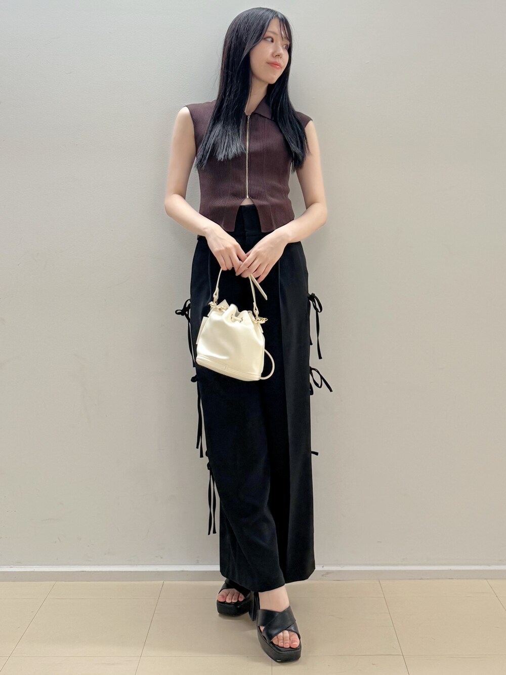 ブラウン系のニット/セーター、ブラック系のその他パンツ、ホワイト系のハンドバッグを着用したレディースの夏コーディネートの2枚目の写真