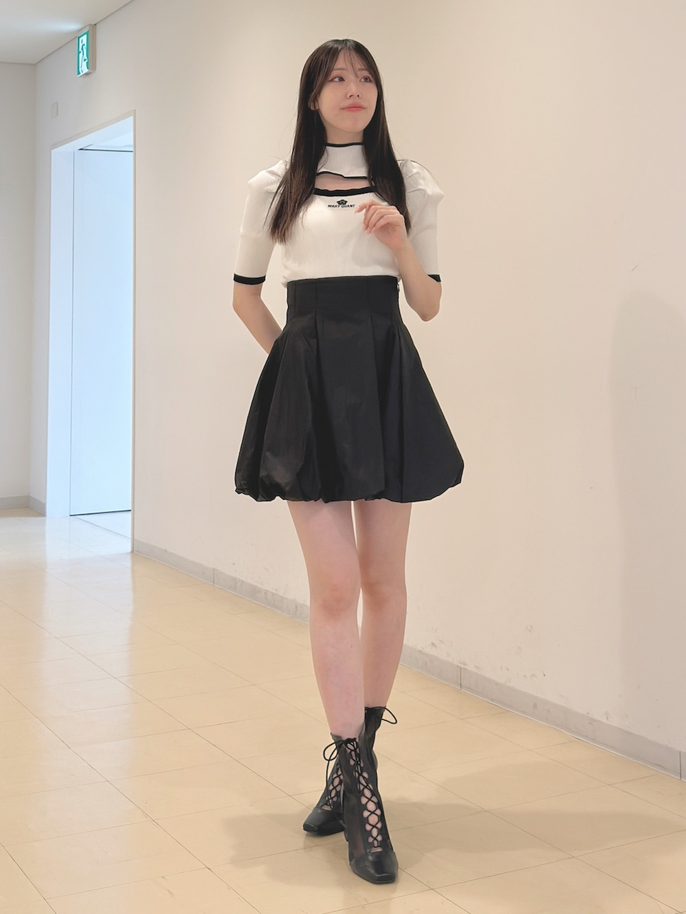 ホワイト系のニット/セーター、ブラック系のスカート、ブラック系のブーツを着用したレディースの春コーディネートの6枚目の写真