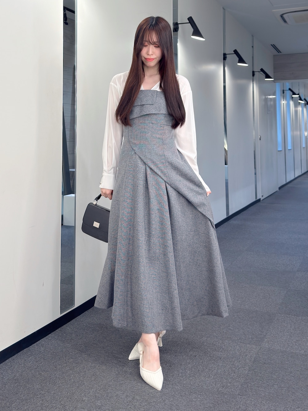 ブラック系のワンピース、ブラック系のハンドバッグ、ホワイト系のパンプスを着用したレディースの春コーディネートの2枚目の写真