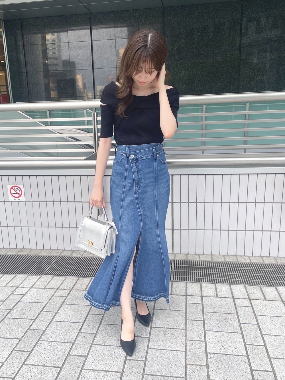 ブラック系のニット/セーター、ブルー系のデニムスカート、シルバー系のハンドバッグを着用したレディースの夏コーディネートの3枚目の写真