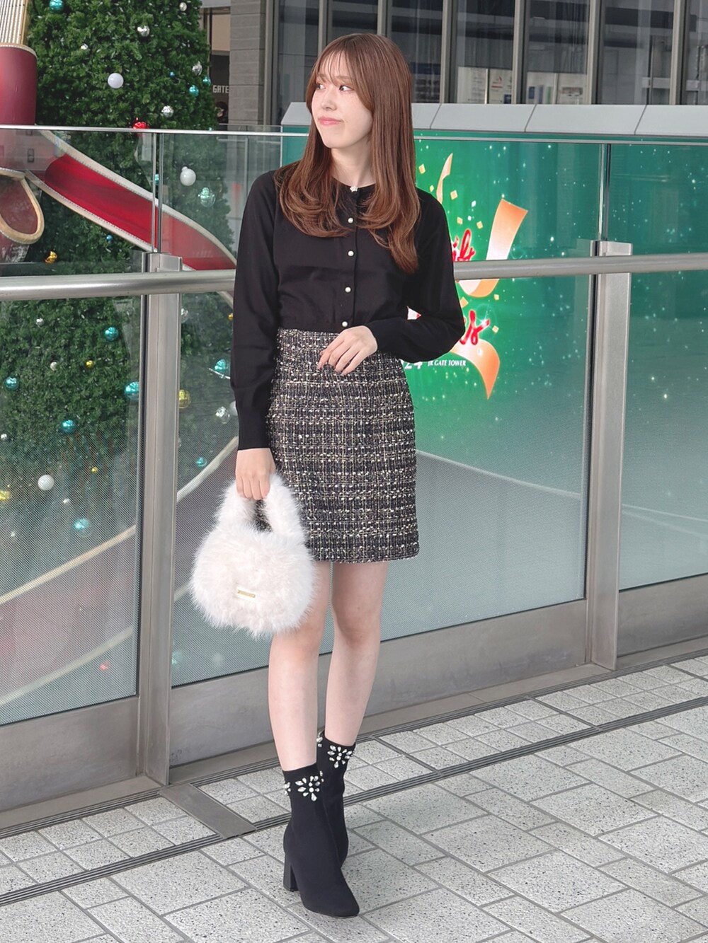 ブラック系のカーディガン/ボレロ、ブラック系のスカート、ホワイト系のハンドバッグを着用したレディースの秋コーディネートの4枚目の写真