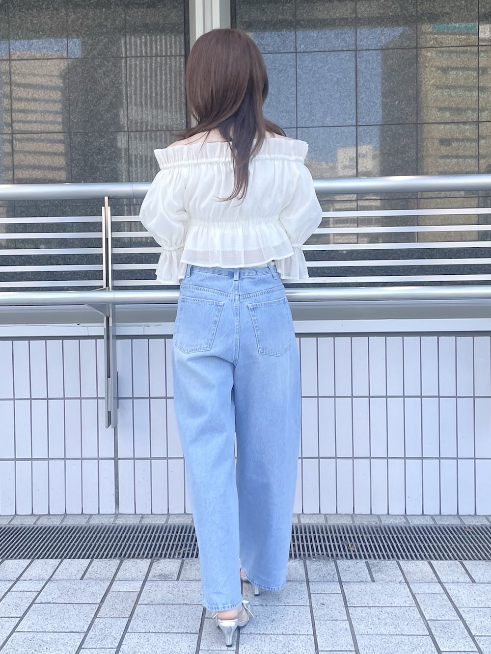 ブルー系のデニムパンツ、シルバー系のハンドバッグ、シルバー系のサンダルを着用したレディースの春コーディネートの5枚目の写真