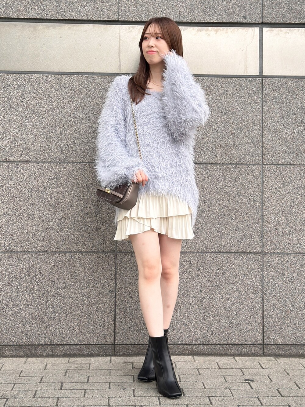 グレー系のニット/セーター、ホワイト系のスカート、ブラック系のブーツを着用したレディースの秋コーディネートの2枚目の写真