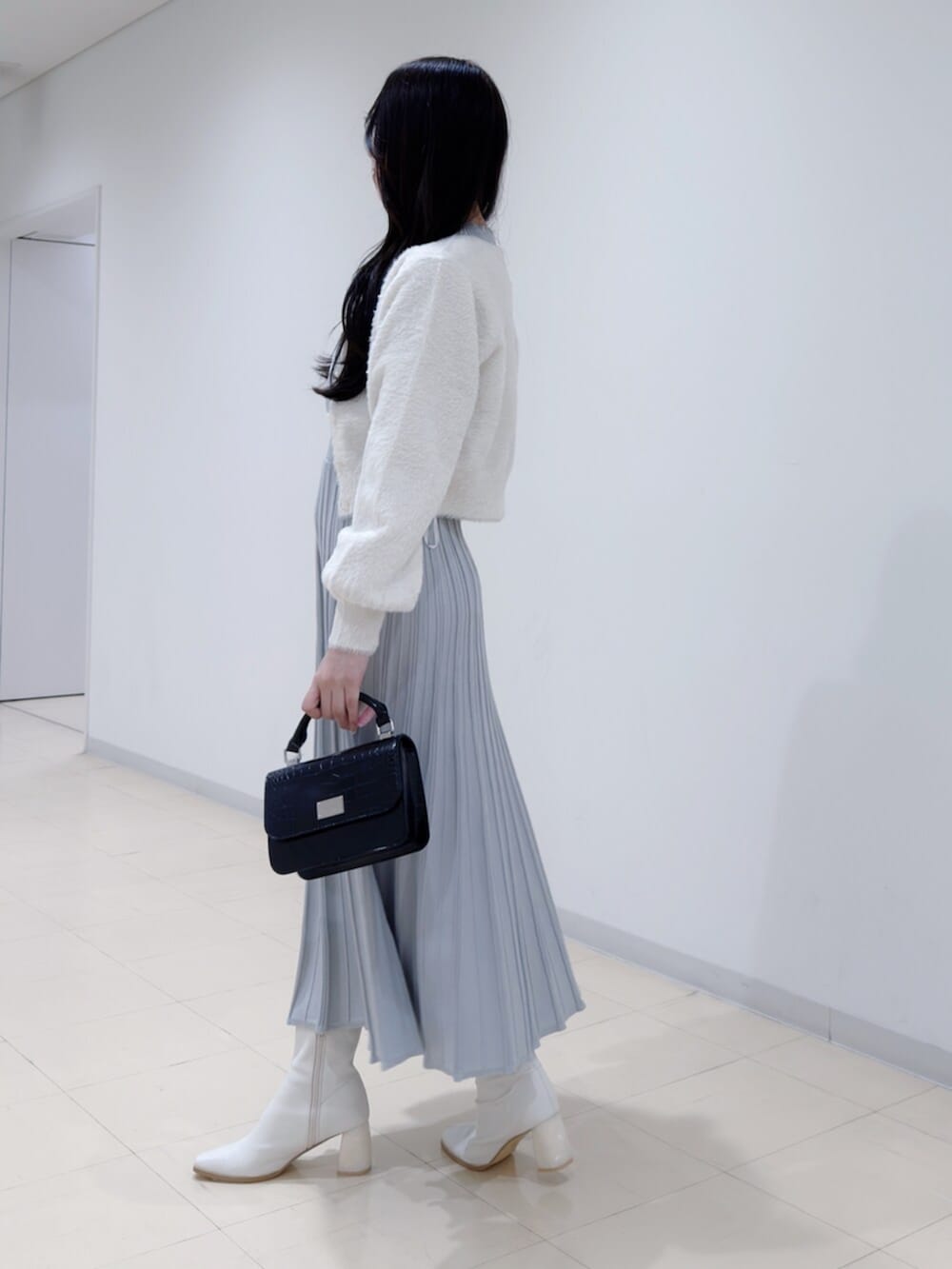 ブラック系のハンドバッグ、ホワイト系のブーツ、ホワイト系のカーディガン/ボレロを着用したレディースの冬コーディネートの3枚目の写真