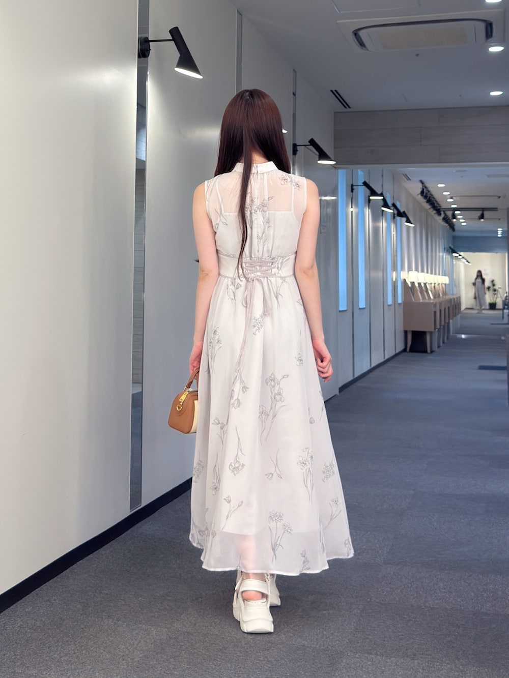 グレー系のワンピース、ブラウン系のハンドバッグ、ホワイト系のサンダルを着用したレディースの夏コーディネートの4枚目の写真