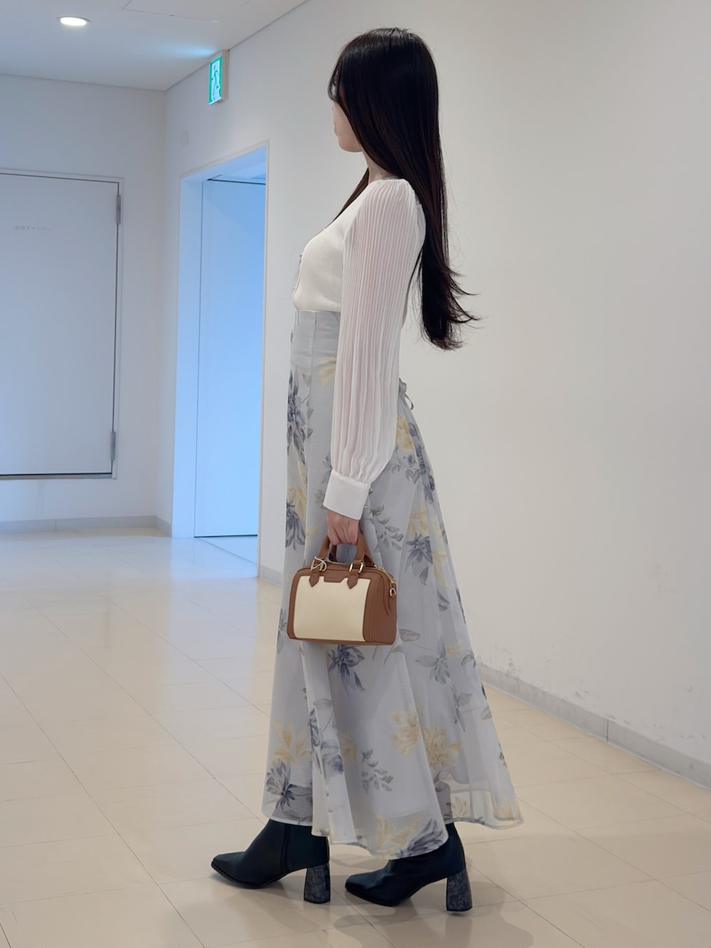 ホワイト系のニット/セーター、グリーン系のスカート、ブラウン系のハンドバッグを着用したレディースの冬コーディネートの3枚目の写真