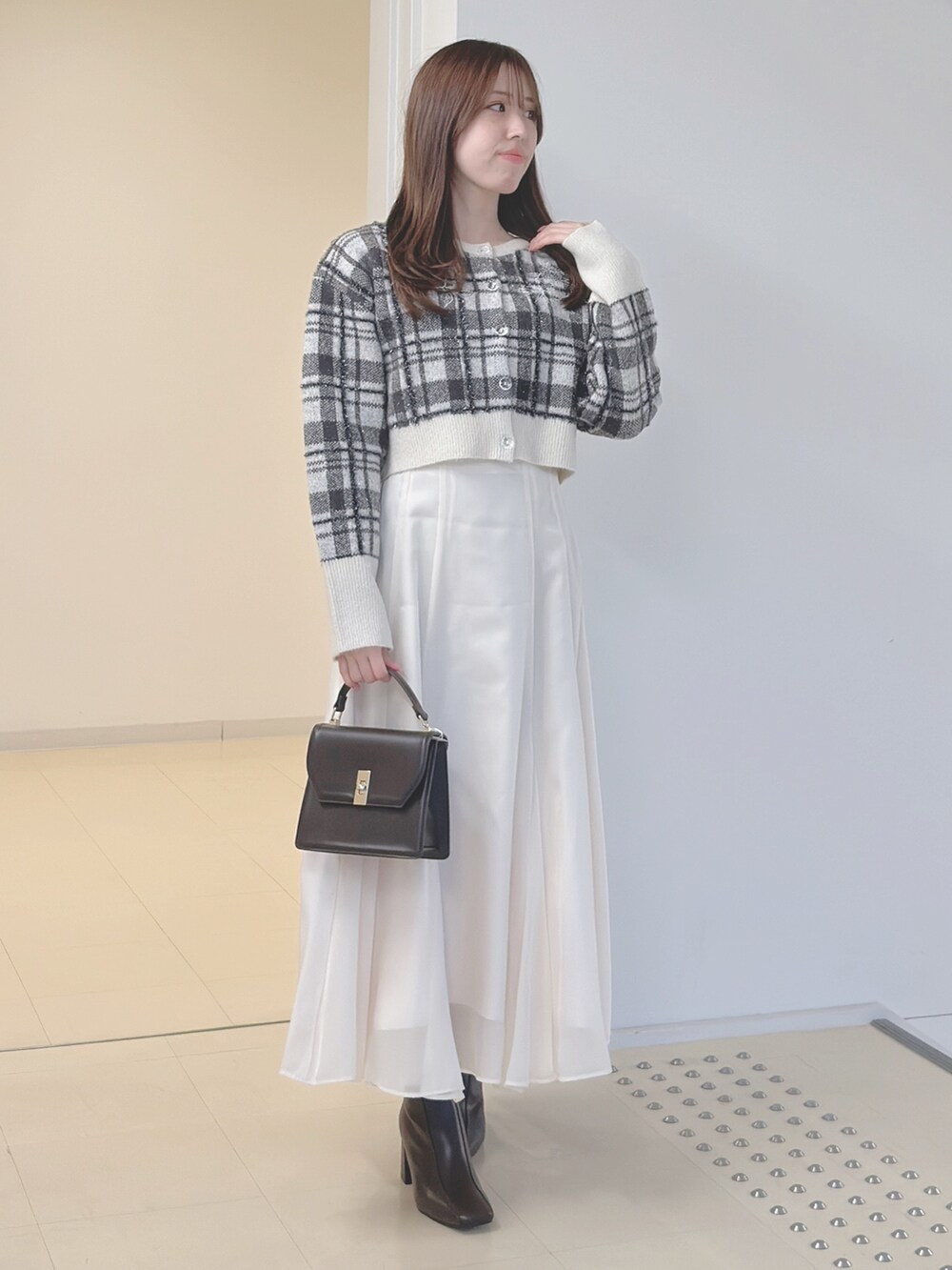 ホワイト系のカーディガン/ボレロ、ブラウン系のハンドバッグ、ホワイト系のスカートを着用したレディースの秋コーディネートの3枚目の写真