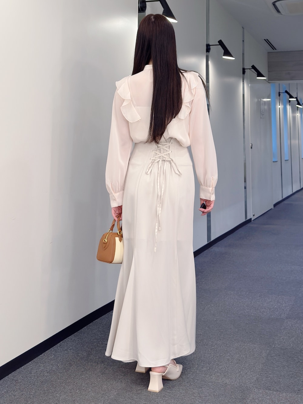 ピンク系のシャツ/ブラウス、ホワイト系のスカート、ブラウン系のハンドバッグを着用したレディースの春コーディネートの5枚目の写真