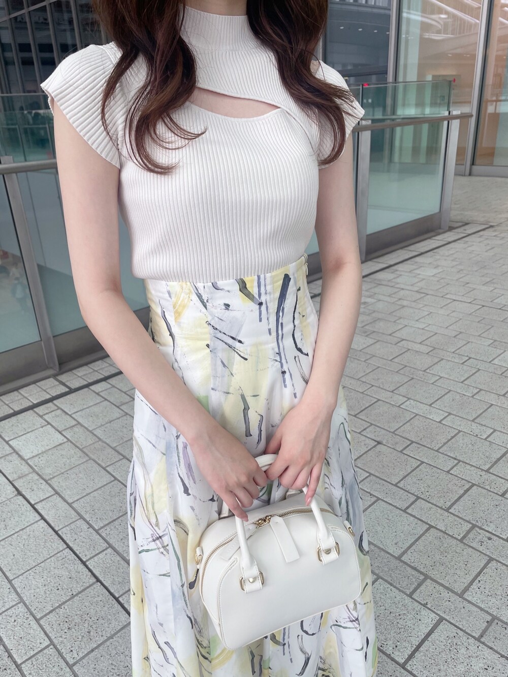 ホワイト系のニット/セーター、イエロー系のスカート、ホワイト系のボストンバッグを着用したレディースの夏コーディネートの6枚目の写真