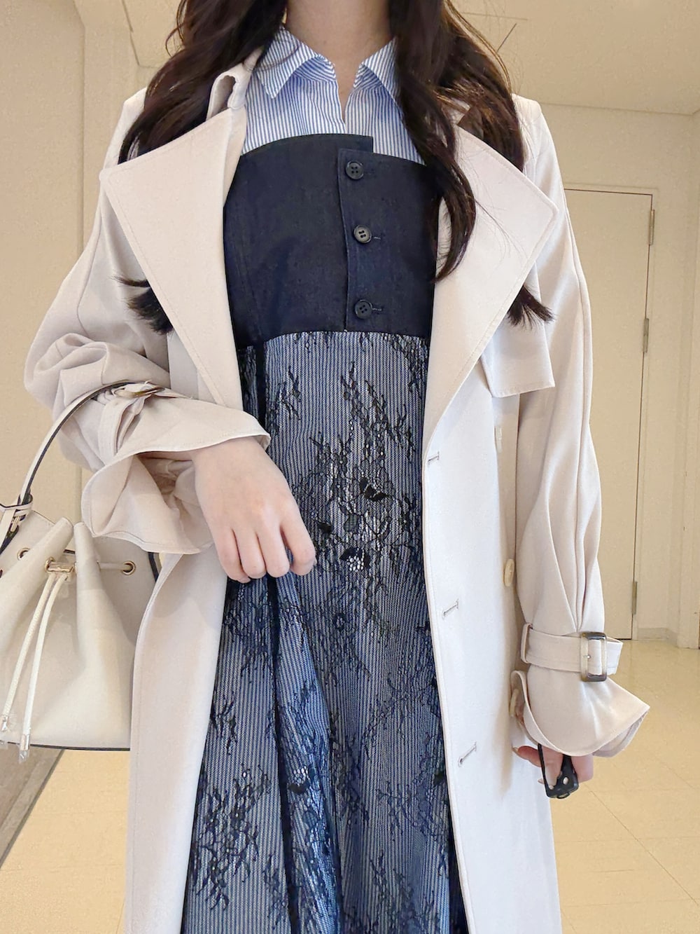 ホワイト系のトレンチコート、ブルー系のワンピース、ホワイト系のブーツを着用したレディースの冬コーディネートの5枚目の写真