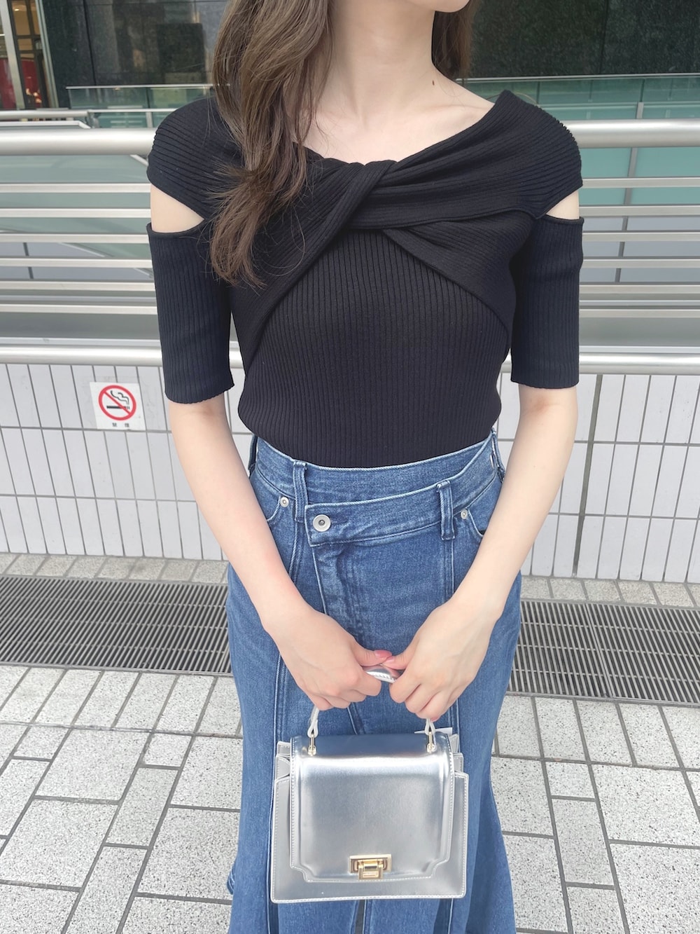 ブラック系のニット/セーター、ブルー系のデニムスカート、シルバー系のハンドバッグを着用したレディースの夏コーディネートの5枚目の写真