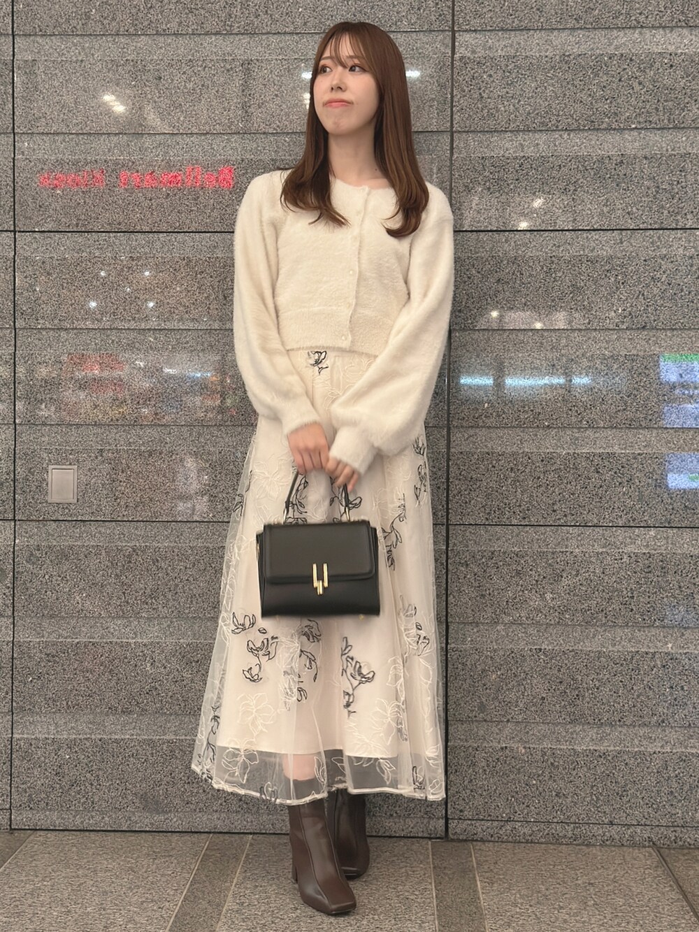 ホワイト系のカーディガン/ボレロ、ホワイト系のスカート、ブラック系のハンドバッグを着用したレディースの秋コーディネートの3枚目の写真