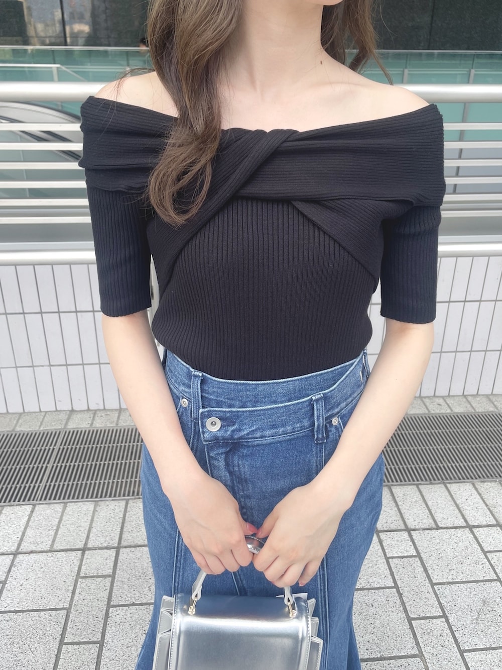 ブラック系のニット/セーター、ブルー系のデニムスカート、シルバー系のハンドバッグを着用したレディースの夏コーディネートの6枚目の写真