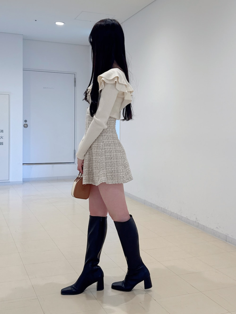 ホワイト系のニット/セーター、ベージュ系のスカート、ブラウン系のハンドバッグを着用したレディースの冬コーディネートの4枚目の写真