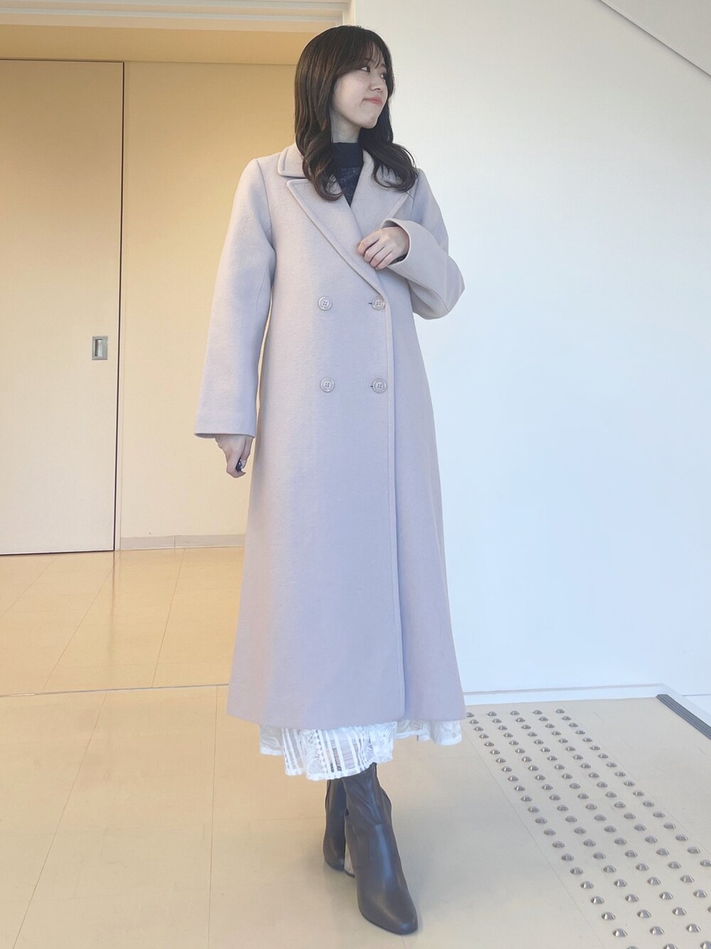 グレー系のニット/セーター、ホワイト系のスカート、ベージュ系のチェスターコートを着用したレディースの秋コーディネートの4枚目の写真