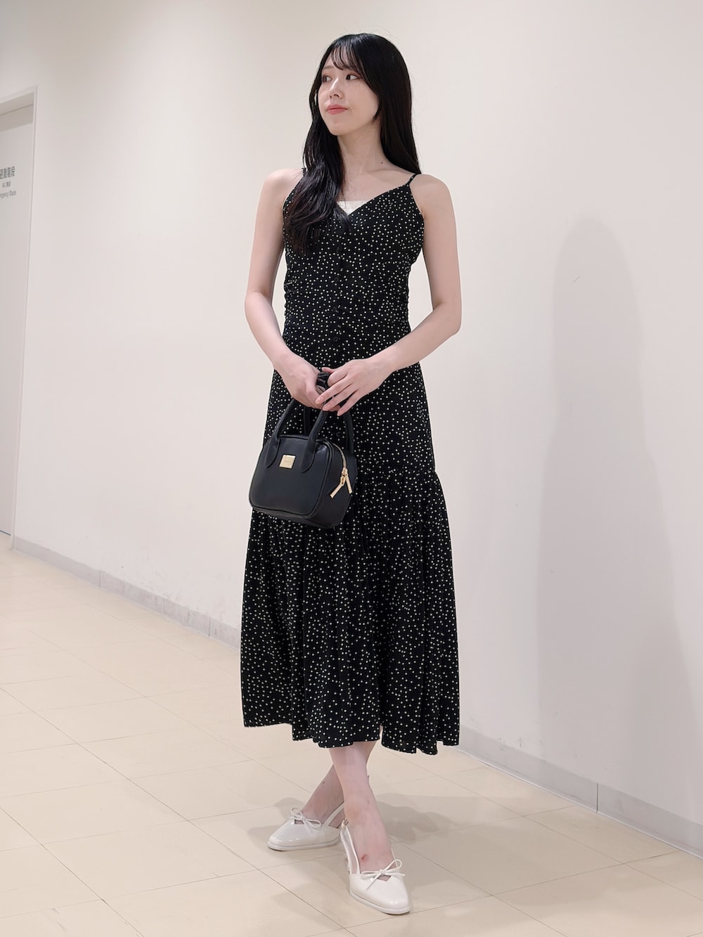 ブラック系のワンピース、ブラック系のハンドバッグ、ホワイト系のパンプスを着用したレディースの秋コーディネートの5枚目の写真