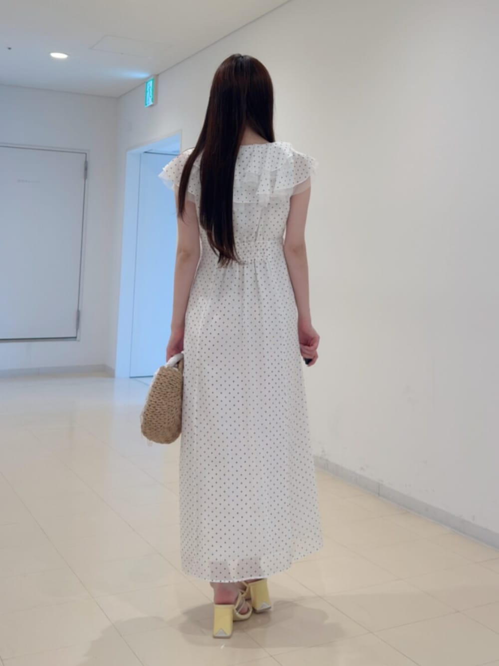 ベージュ系のハンドバッグ、ホワイト系のワンピース、イエロー系のサンダルを着用したレディースの夏コーディネートの4枚目の写真