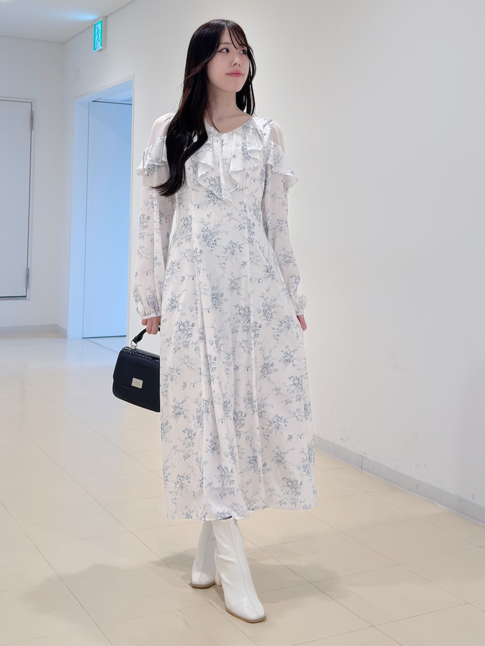 ホワイト系のワンピース、ブラック系のハンドバッグ、ホワイト系のブーツを着用したレディースの冬コーディネートの3枚目の写真