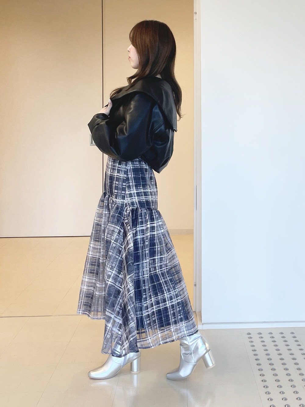 ブルー系のワンピース、シルバー系のブーツ、ブラック系のライダースジャケットを着用したレディースの冬コーディネートの3枚目の写真