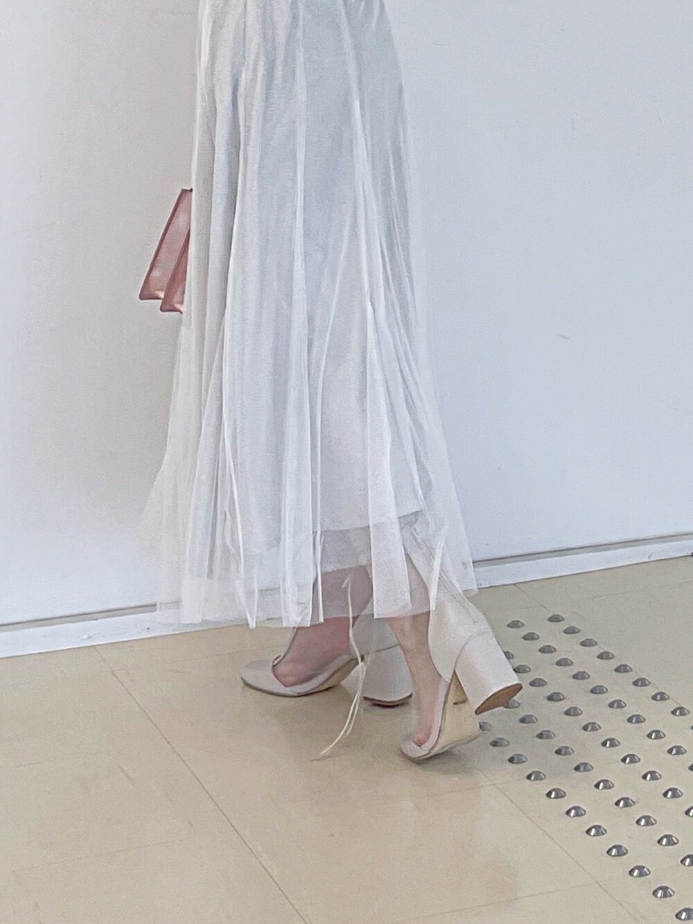 ホワイト系のスウェット、ホワイト系のスカート、ピンク系のハンドバッグを着用したレディースの秋コーディネートの7枚目の写真