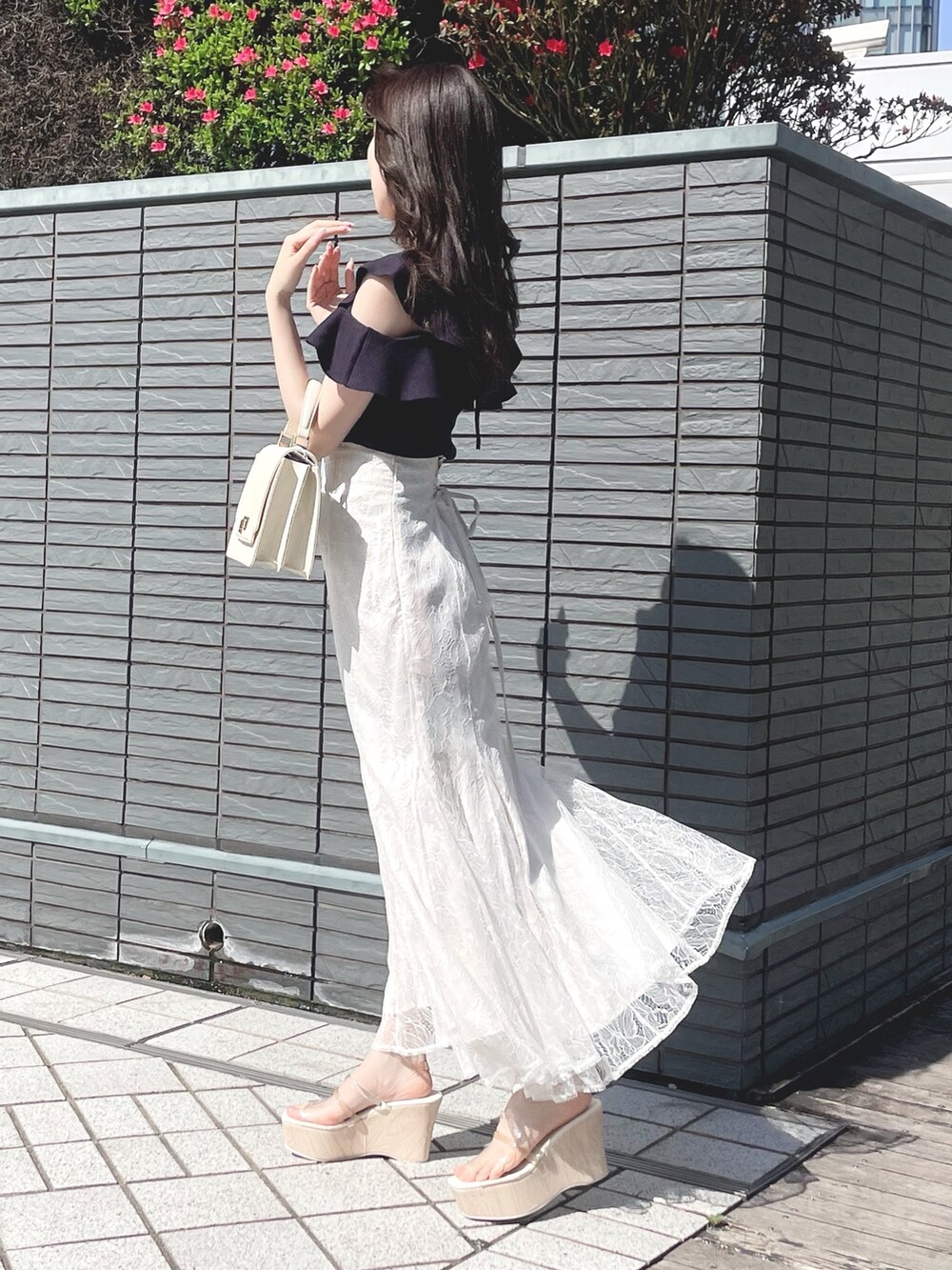 ブルー系のニット/セーター、ホワイト系のスカート、ホワイト系のハンドバッグを着用したレディースの春コーディネートの6枚目の写真