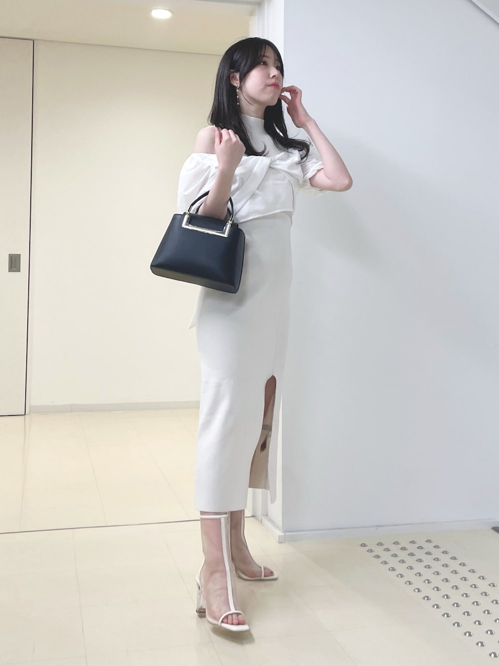 ホワイト系のワンピース、ブラック系のハンドバッグ、ホワイト系のブーツを着用したレディースの春コーディネートの3枚目の写真