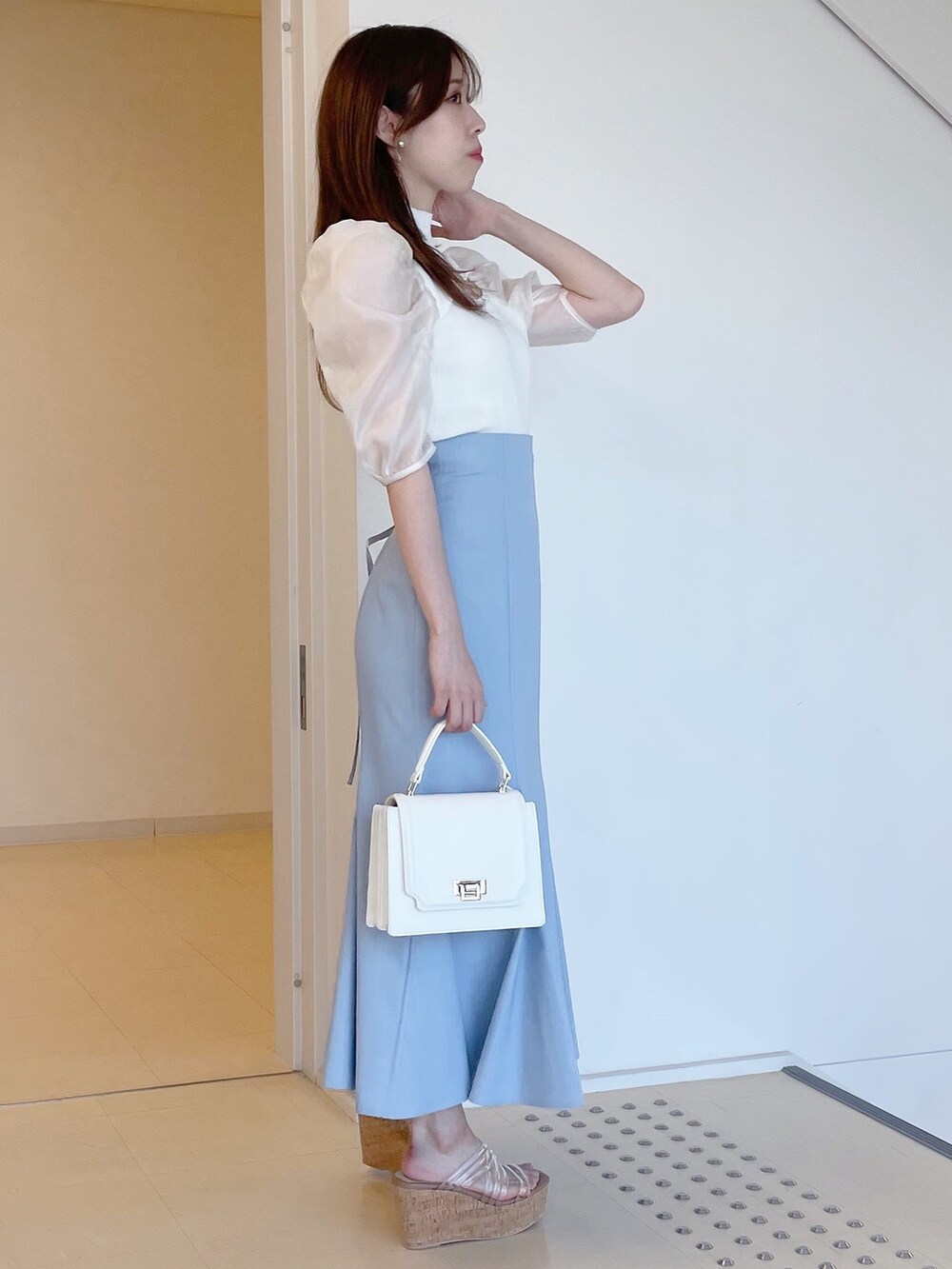 ホワイト系のニット/セーター、ブルー系のスカート、ホワイト系のハンドバッグを着用したレディースの夏コーディネートの3枚目の写真