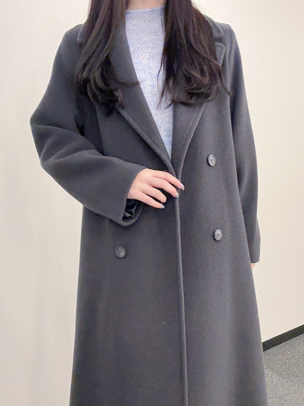 グレー系のチェスターコート、ブルー系のワンピース、ホワイト系のハンドバッグを着用したレディースの秋コーディネートの5枚目の写真