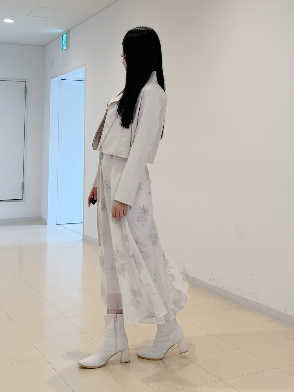 ホワイト系のライダースジャケット、ベージュ系のワンピース、ホワイト系のブーツを着用したレディースの秋コーディネートの4枚目の写真