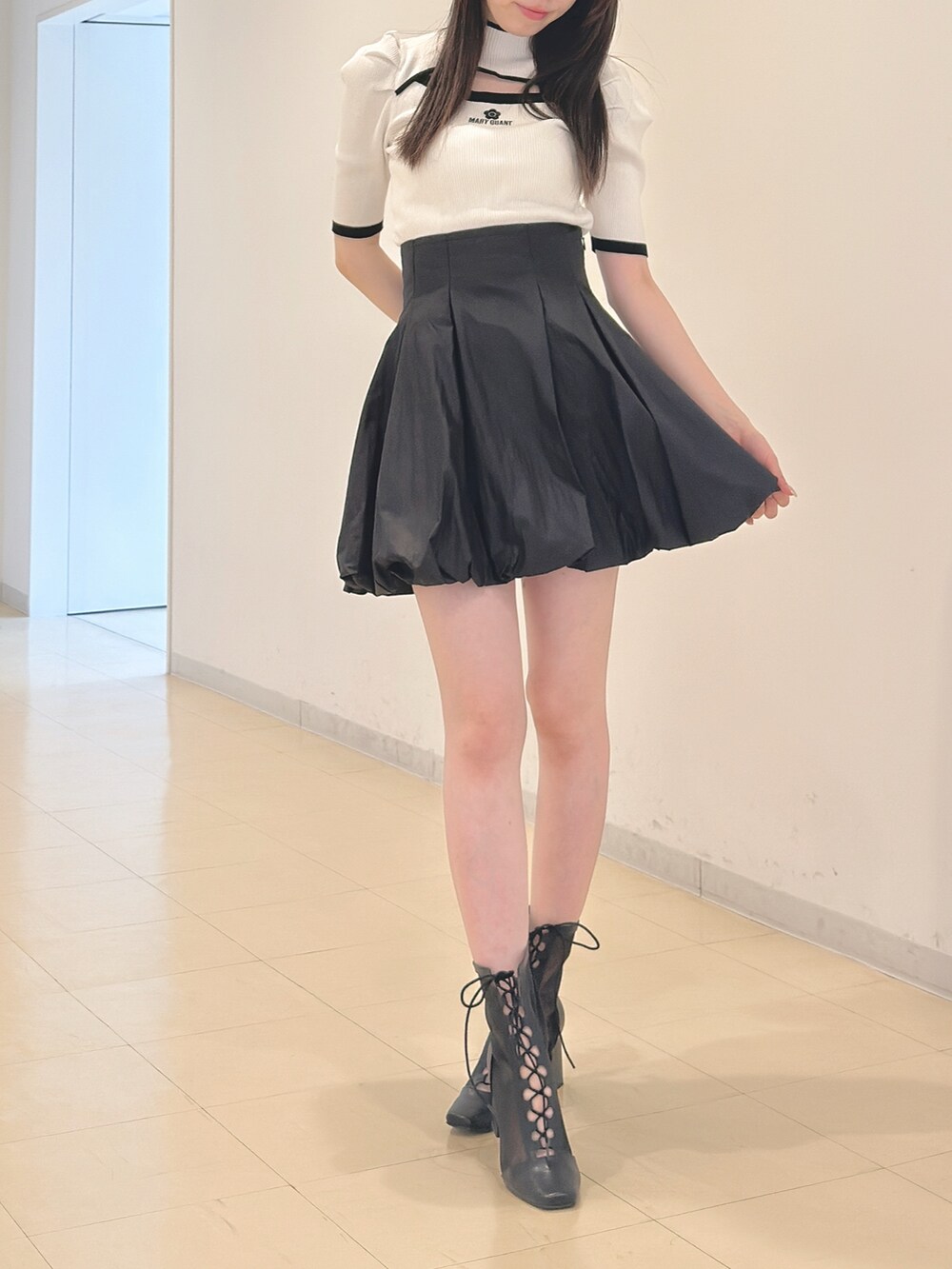 ホワイト系のニット/セーター、ブラック系のスカート、ブラック系のブーツを着用したレディースの春コーディネートの2枚目の写真