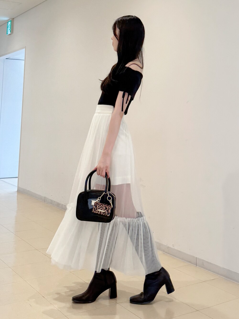 ブラック系のニット/セーター、ホワイト系のスカート、ブラック系のハンドバッグを着用したレディースの夏コーディネートの4枚目の写真