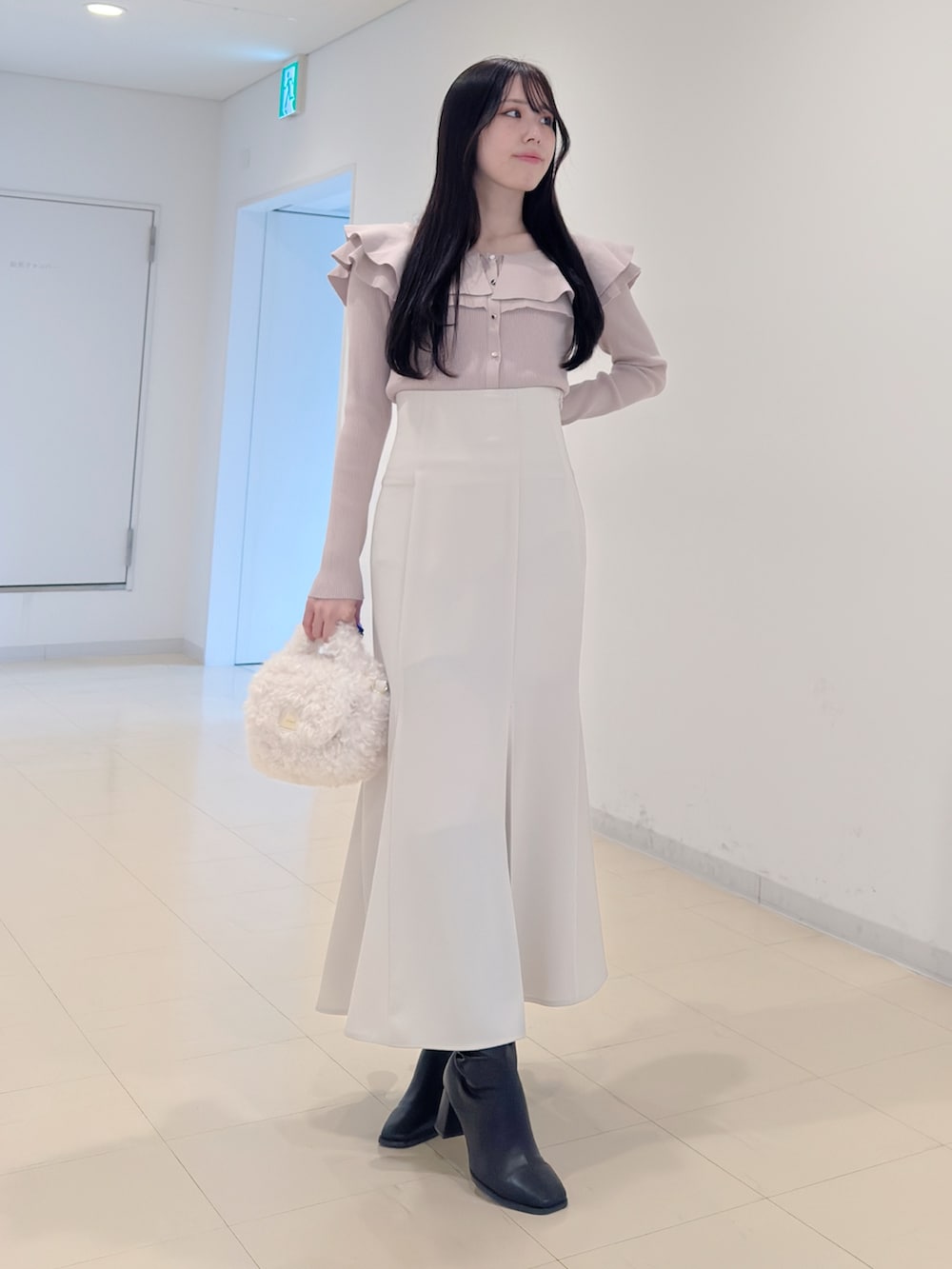 ベージュ系のニット/セーター、ホワイト系のスカート、ホワイト系のハンドバッグを着用したレディースの冬コーディネートの5枚目の写真