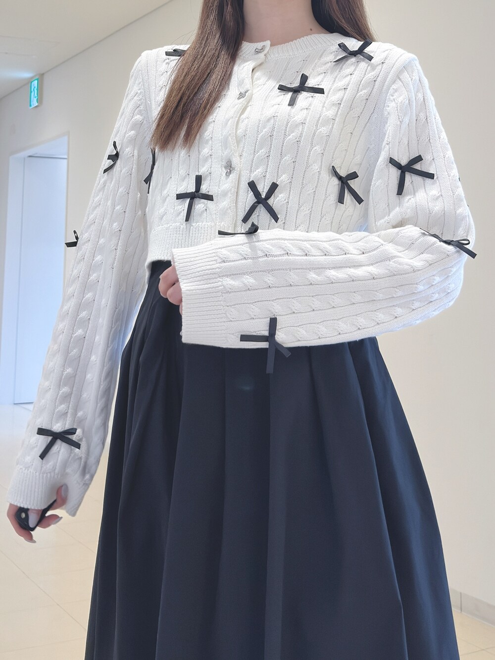 ホワイト系のカーディガン/ボレロ、ブラック系のスカート、ブラウン系のブーツを着用したレディースの春コーディネートの7枚目の写真