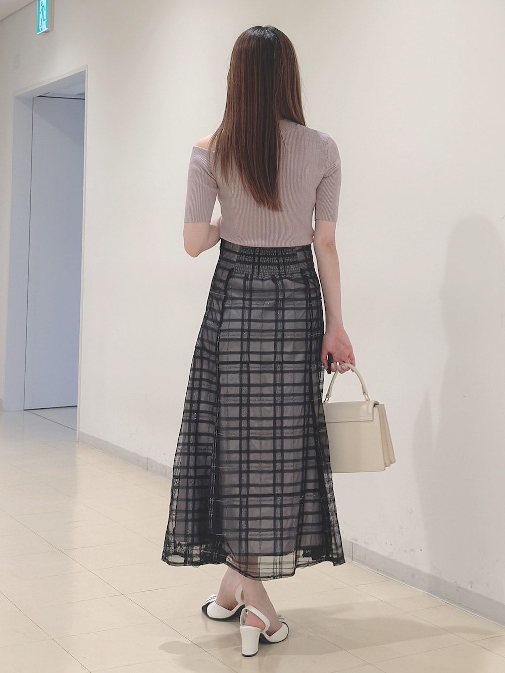 ベージュ系のニット/セーター、ブルー系のスカート、ホワイト系のハンドバッグを着用したレディースの春コーディネートの5枚目の写真