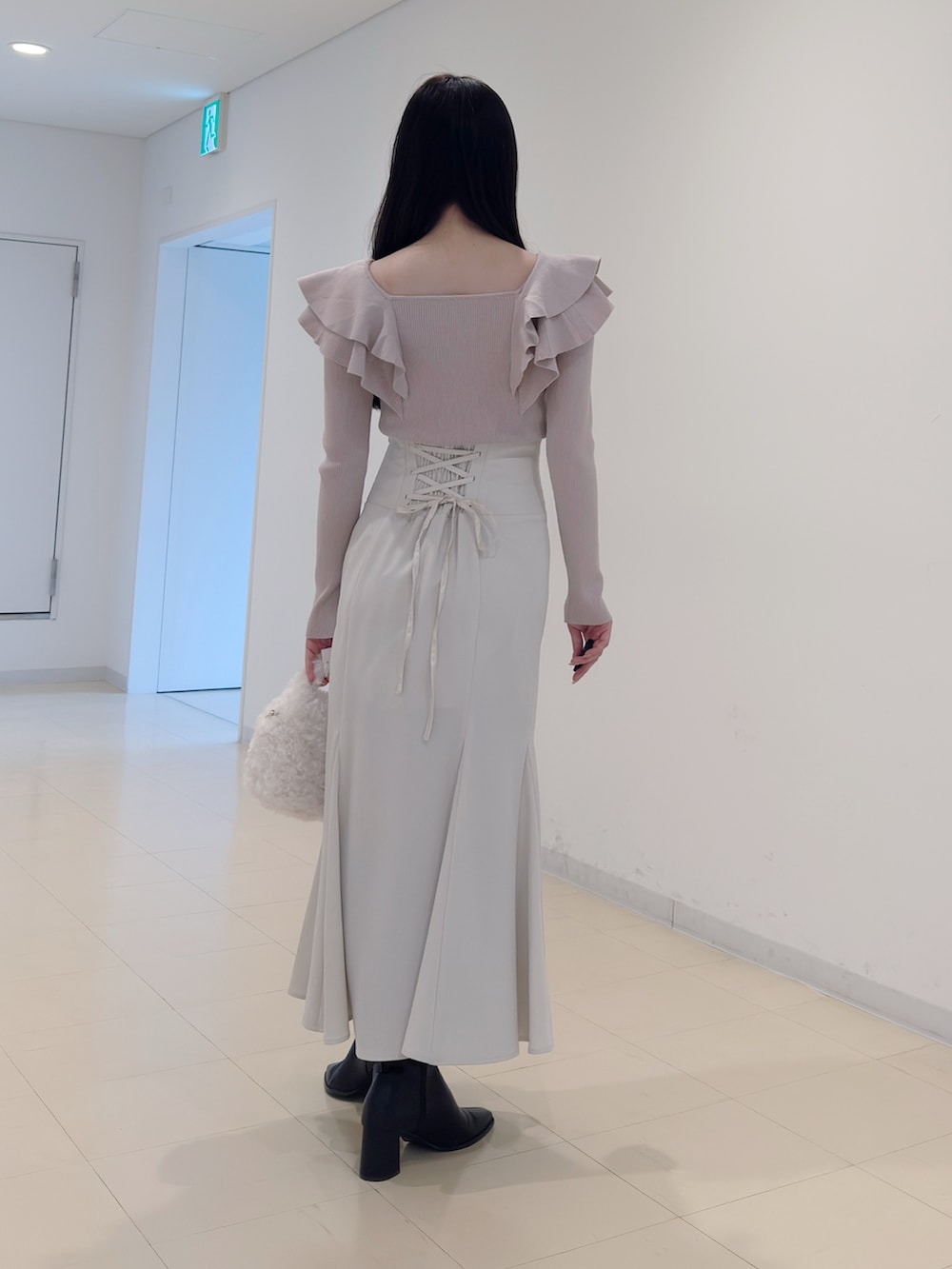 ベージュ系のニット/セーター、ホワイト系のスカート、ホワイト系のハンドバッグを着用したレディースの冬コーディネートの4枚目の写真