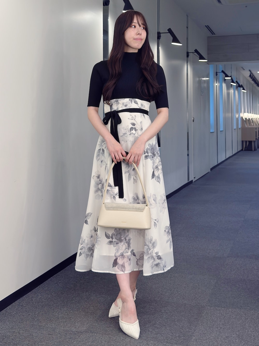 ブラック系のワンピース、ホワイト系のハンドバッグ、ホワイト系のパンプスを着用したレディースの春コーディネートの4枚目の写真