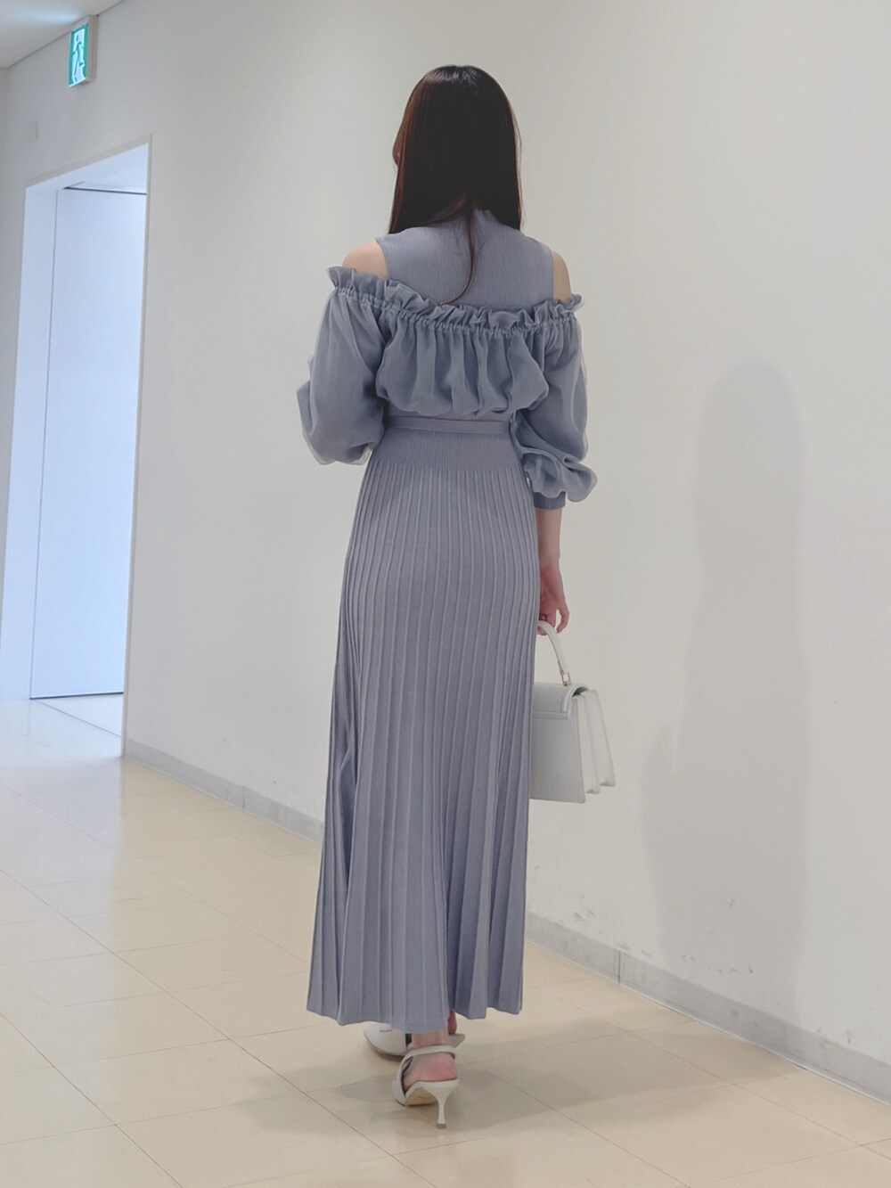 ブルー系のワンピース、ホワイト系のハンドバッグ、ホワイト系のパンプスを着用したレディースの冬コーディネートの5枚目の写真