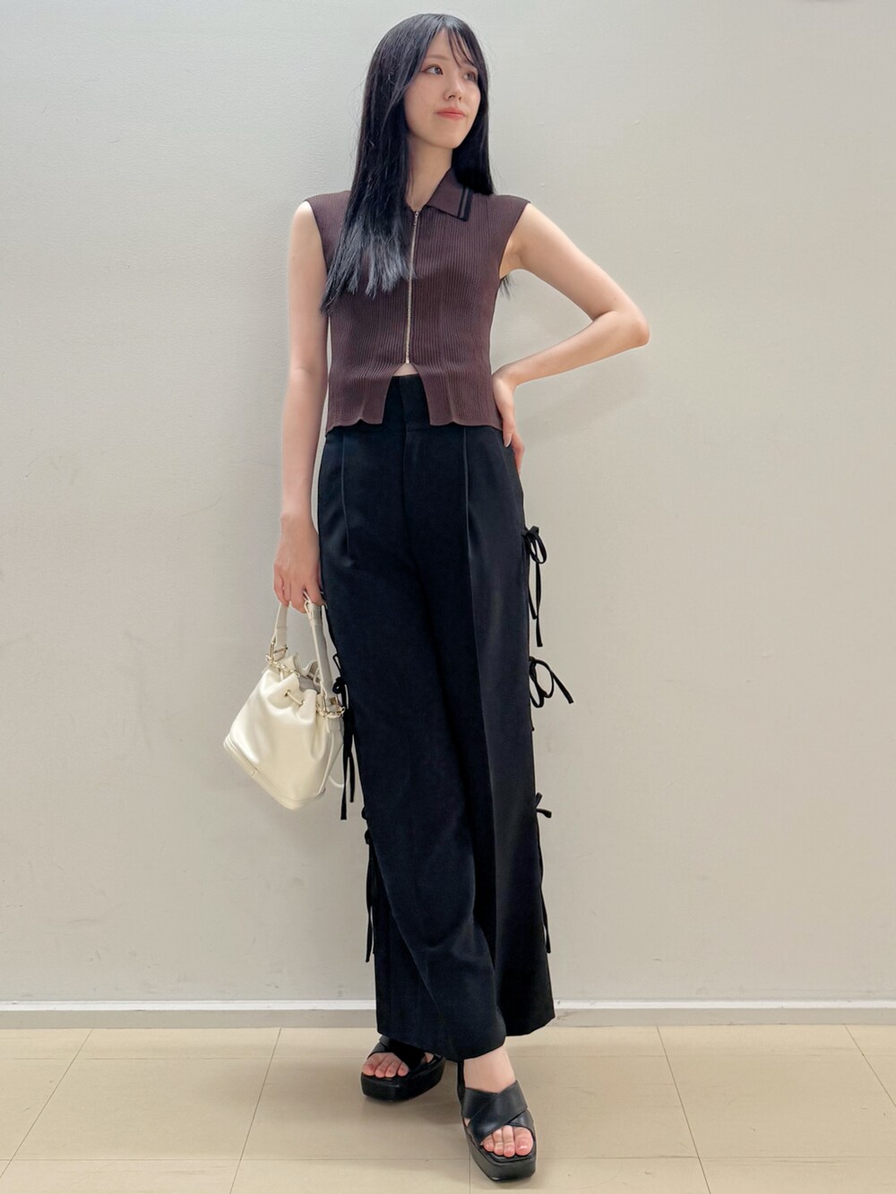 ブラウン系のニット/セーター、ブラック系のその他パンツ、ホワイト系のハンドバッグを着用したレディースの夏コーディネートの3枚目の写真