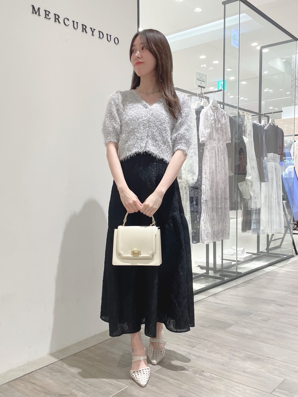 ブラック系のスカート、ホワイト系のパンプス、ホワイト系のカーディガン/ボレロを着用したレディースの冬コーディネートの3枚目の写真