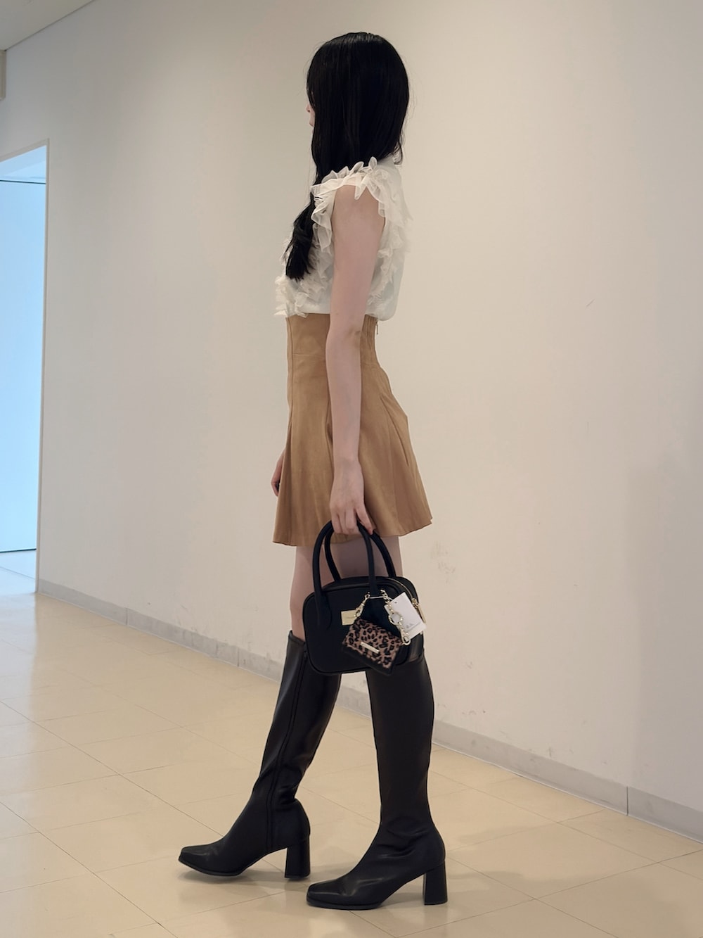 ホワイト系のニット/セーター、ブラック系のハンドバッグ、イエロー系のスカートを着用したレディースの夏コーディネートの4枚目の写真