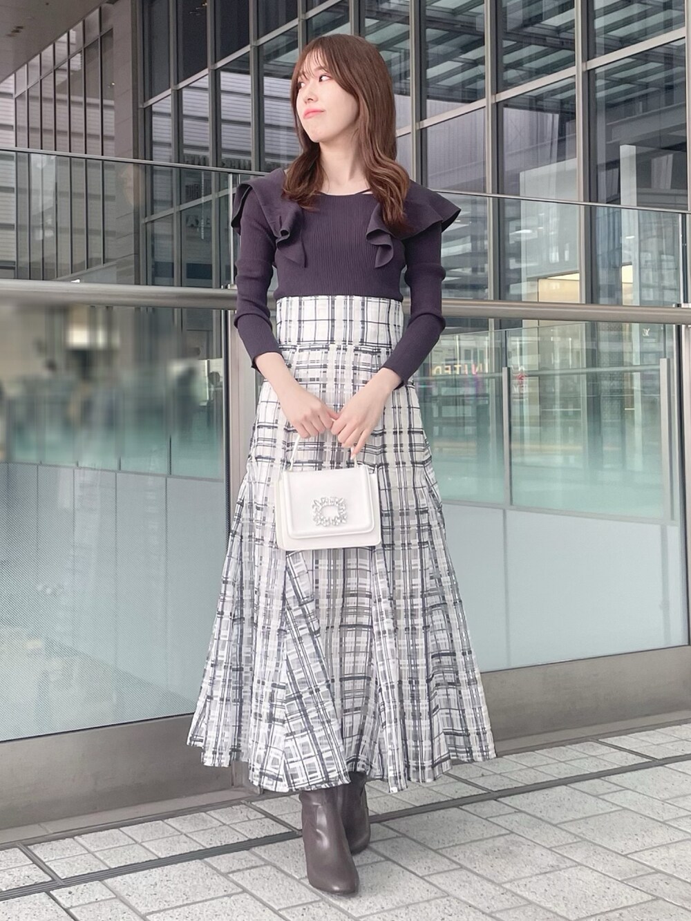 ホワイト系のショルダーバッグ、グレー系のニット/セーター、ホワイト系のチェスターコートを着用したレディースの冬コーディネートの3枚目の写真