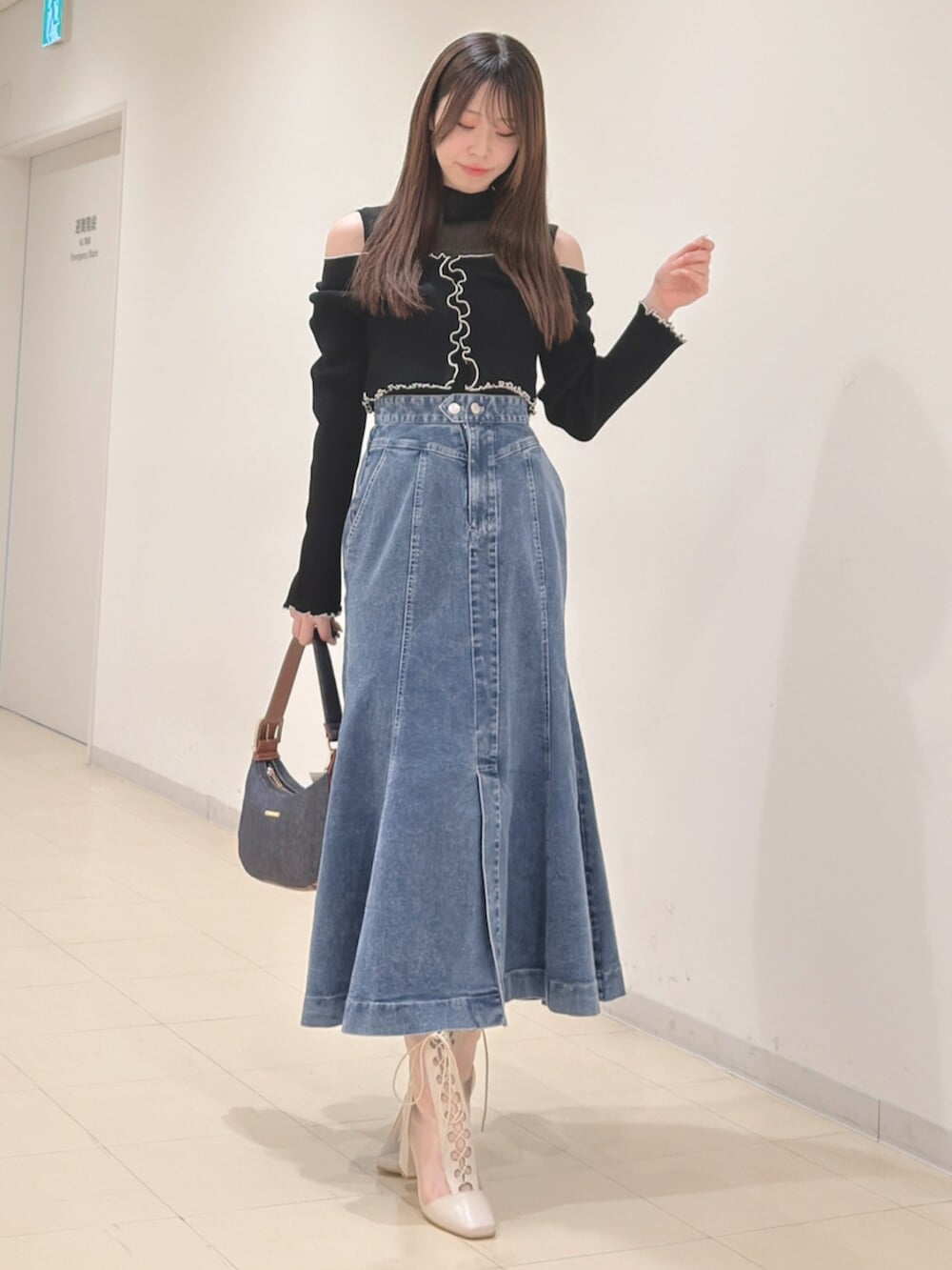 ホワイト系のブーツ、ブルー系のショルダーバッグ、ブラック系のニット/セーターを着用したレディースの春コーディネートの2枚目の写真