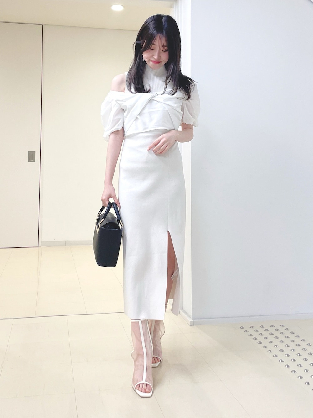 ホワイト系のワンピース、ブラック系のハンドバッグ、ホワイト系のブーツを着用したレディースの春コーディネートの4枚目の写真