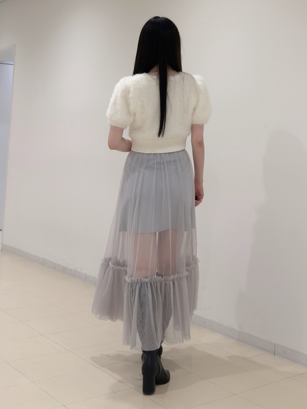 ホワイト系のニット/セーター、ブルー系のスカート、ブラック系のブーツを着用したレディースの夏コーディネートの5枚目の写真