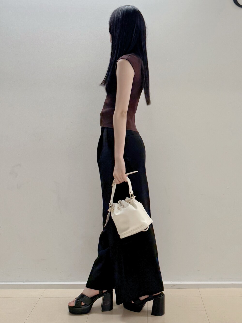 ブラウン系のニット/セーター、ブラック系のその他パンツ、ホワイト系のハンドバッグを着用したレディースの夏コーディネートの4枚目の写真