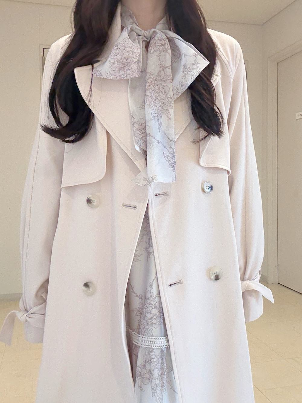 ピンク系のトレンチコート、ベージュ系のワンピース、ホワイト系のショルダーバッグを着用したレディースの冬コーディネートの5枚目の写真