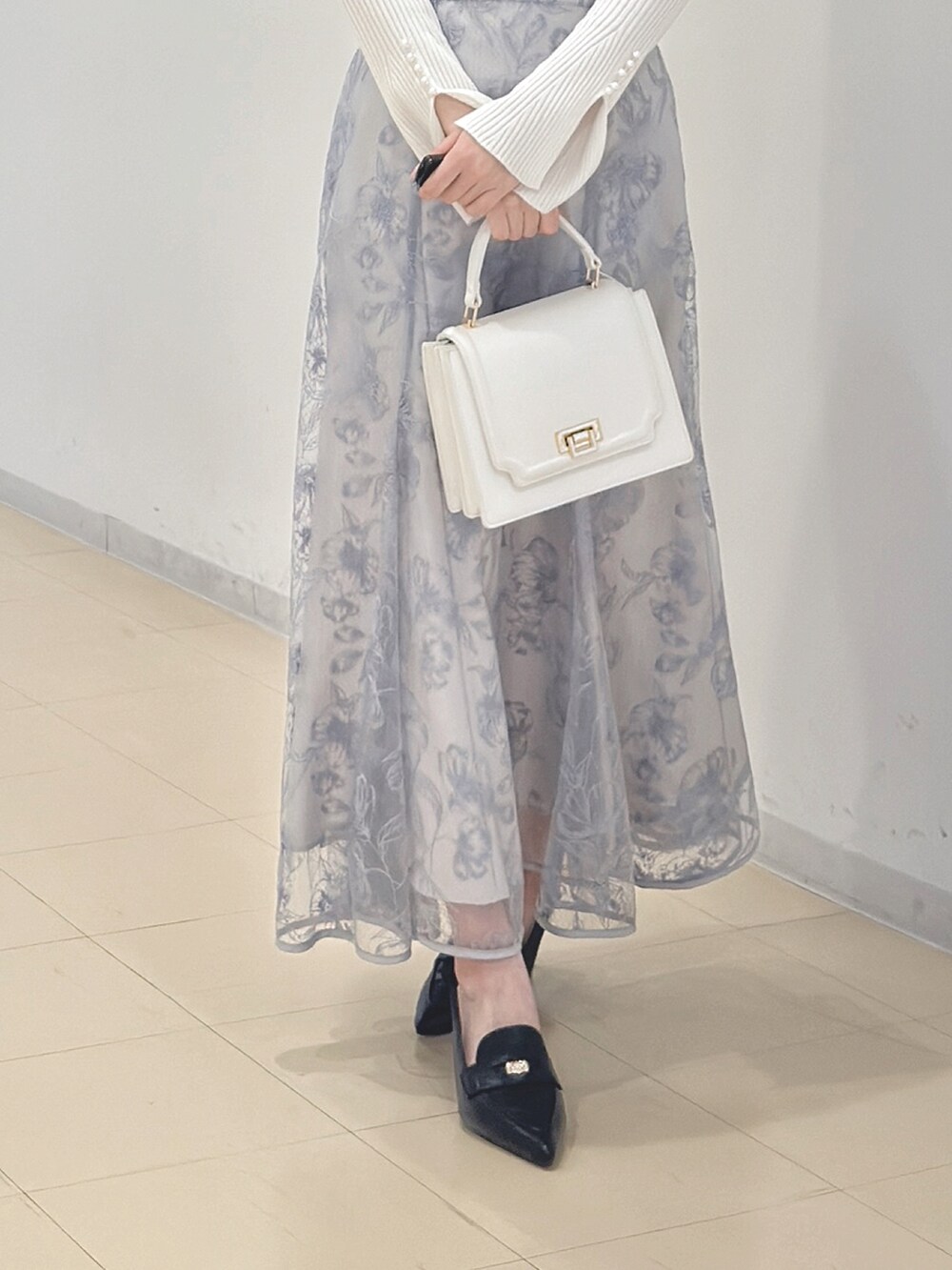 ホワイト系のニット/セーター、ブルー系のスカート、ホワイト系のハンドバッグを着用したレディースの冬コーディネートの6枚目の写真