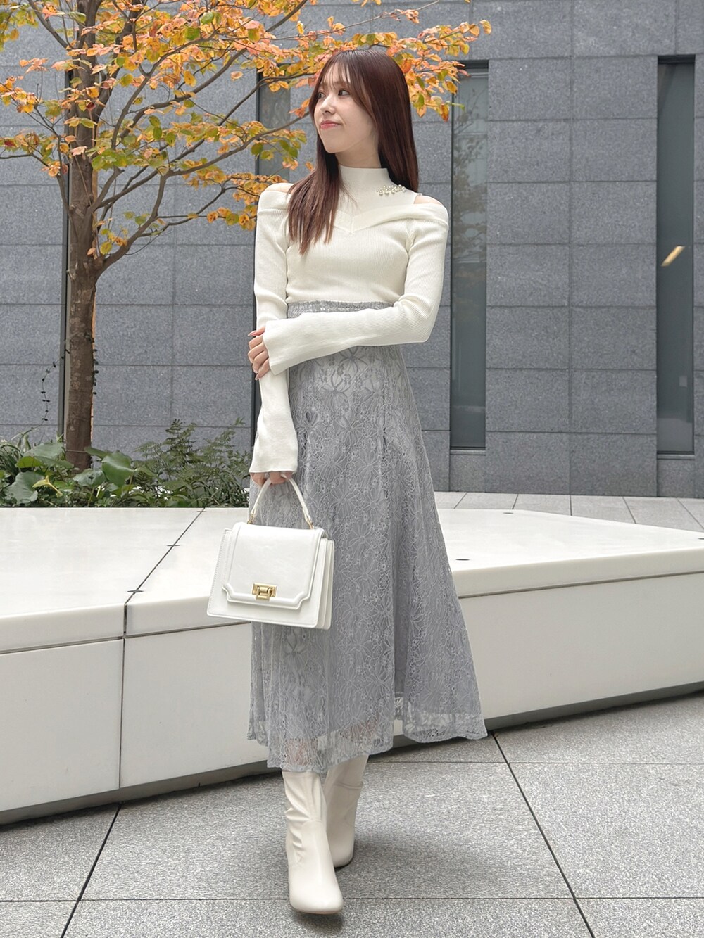 ホワイト系のハンドバッグ、ホワイト系のブーツ、ホワイト系のニット/セーターを着用したレディースの冬コーディネートの3枚目の写真