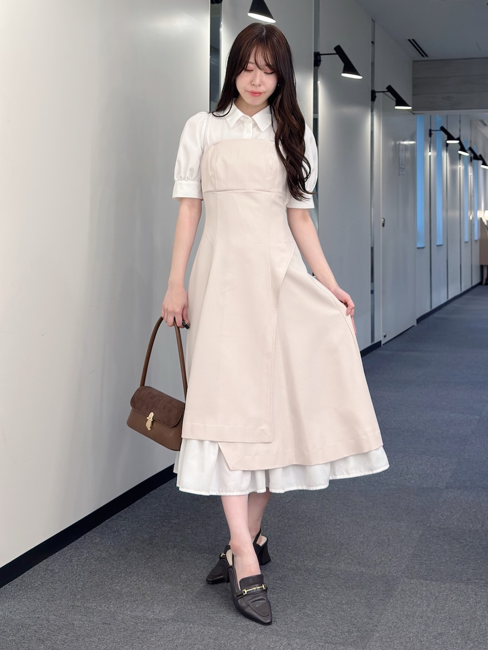 ベージュ系のワンピース、ブラウン系のハンドバッグ、ブラウン系のパンプスを着用したレディースの春コーディネートの2枚目の写真